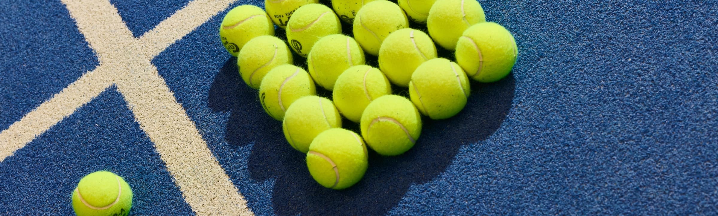Padelbolde lagt i en trekant på en blå bane ved en hvid banelinje